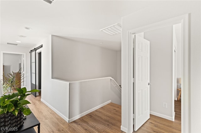 hallway with light hardwood / wood-style flooring and a barn door