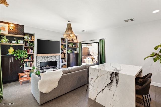 living room featuring a fireplace, built in features, and a chandelier