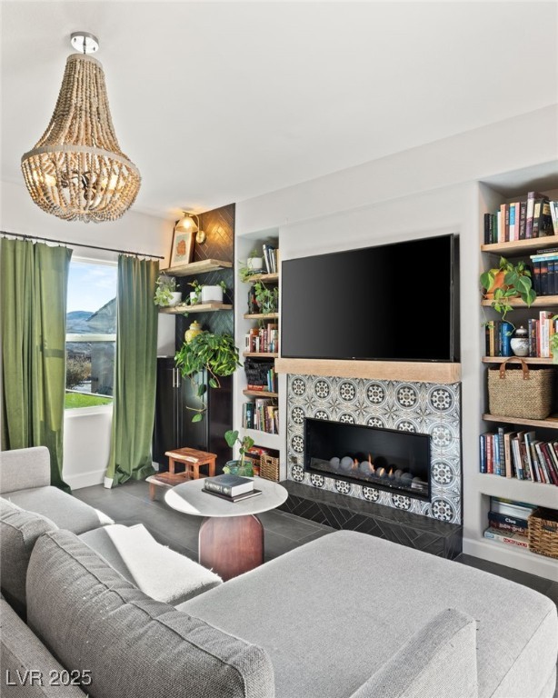 living room with built in features, an inviting chandelier, and a fireplace