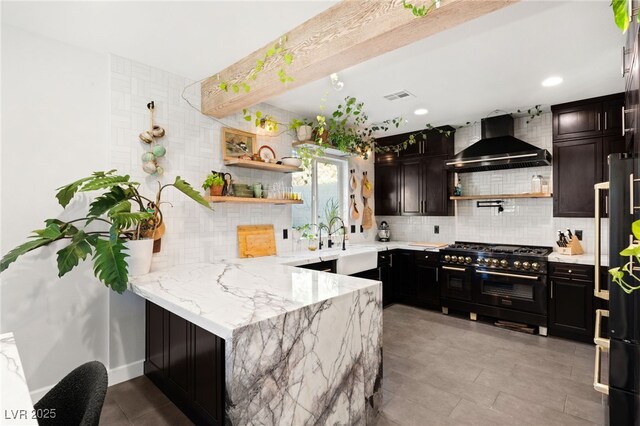 kitchen featuring kitchen peninsula, light stone countertops, premium appliances, sink, and wall chimney range hood