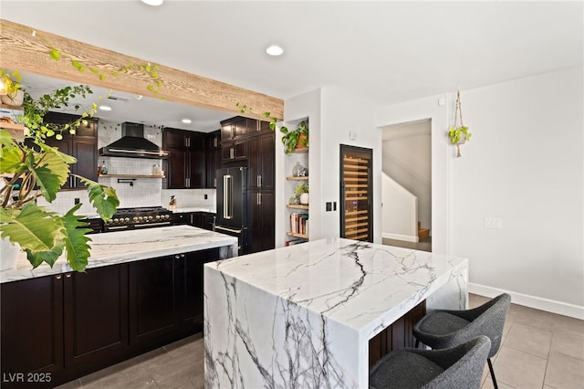 kitchen featuring wall chimney exhaust hood, backsplash, light stone counters, a kitchen island, and high end appliances