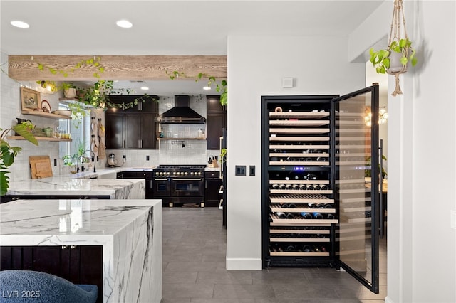 interior space featuring wall chimney exhaust hood, sink, backsplash, light stone counters, and double oven range