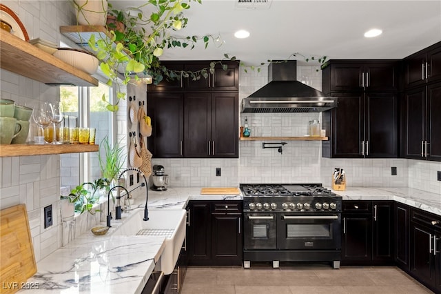 kitchen featuring light stone countertops, light tile patterned flooring, wall chimney range hood, decorative backsplash, and high end stove