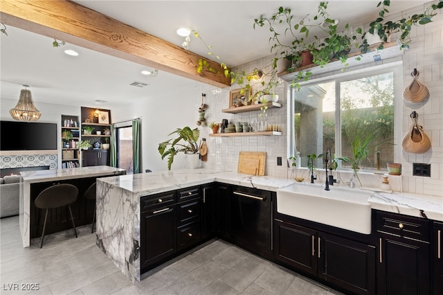 kitchen featuring kitchen peninsula, sink, tasteful backsplash, and light stone countertops