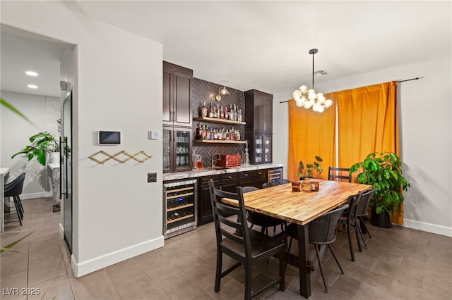 dining area featuring tile patterned flooring, indoor bar, an inviting chandelier, and wine cooler