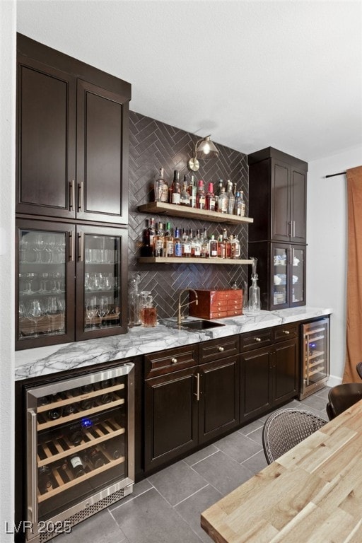 bar with sink, dark brown cabinets, decorative backsplash, and wine cooler