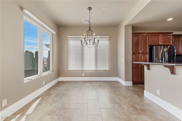 kitchen with a kitchen bar, stainless steel refrigerator with ice dispenser, an inviting chandelier, and hanging light fixtures