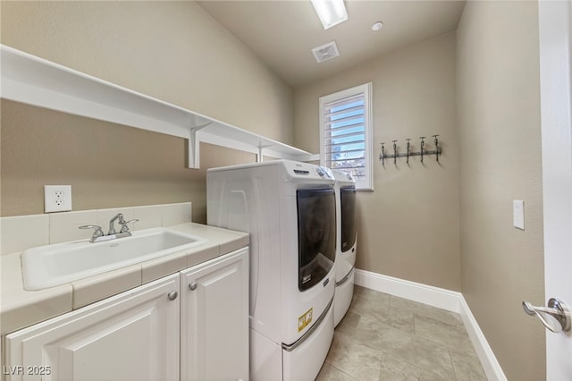 clothes washing area with washing machine and dryer, sink, and cabinets