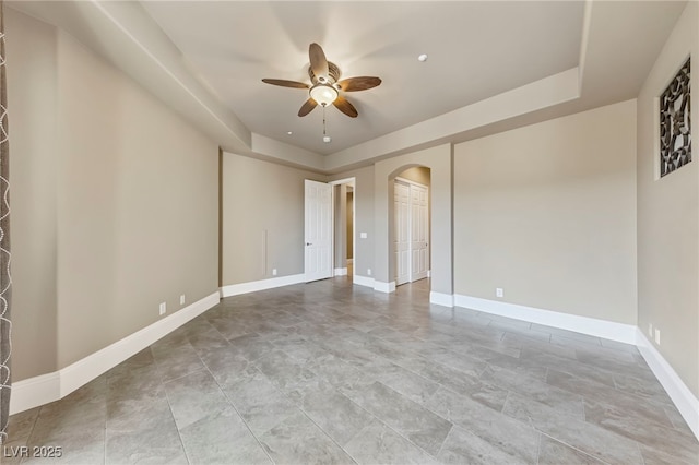 unfurnished room featuring a raised ceiling and ceiling fan