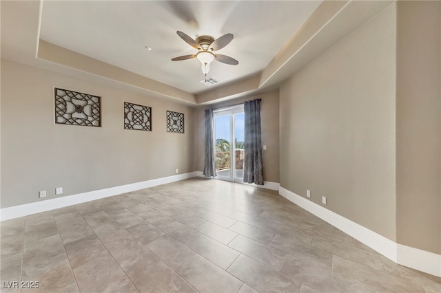 tiled spare room featuring a raised ceiling and ceiling fan