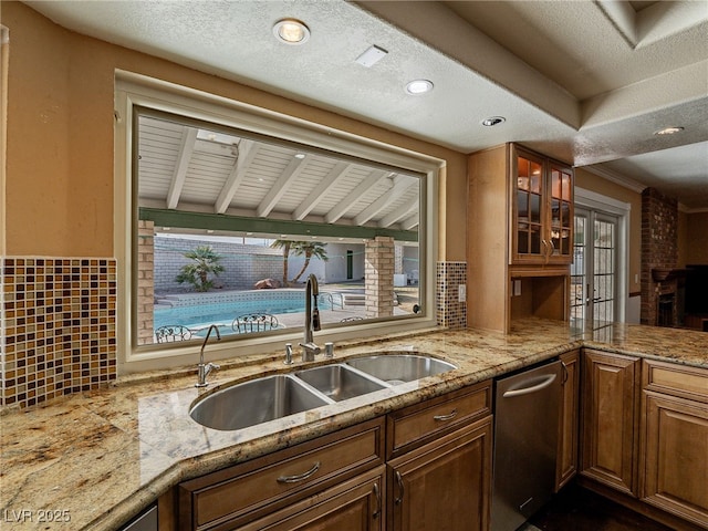 kitchen featuring dishwasher, light stone countertops, and sink