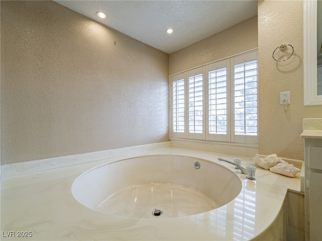 bathroom with a bathtub, vanity, and a textured ceiling