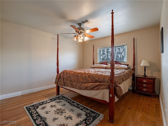 bedroom with hardwood / wood-style flooring, ceiling fan, and a textured ceiling