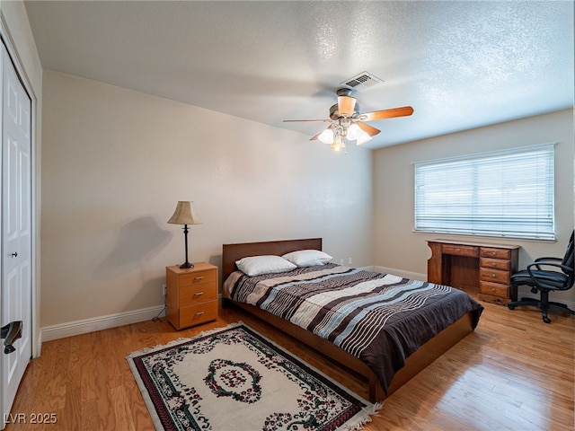 bedroom featuring ceiling fan, light wood-type flooring, a textured ceiling, and a closet