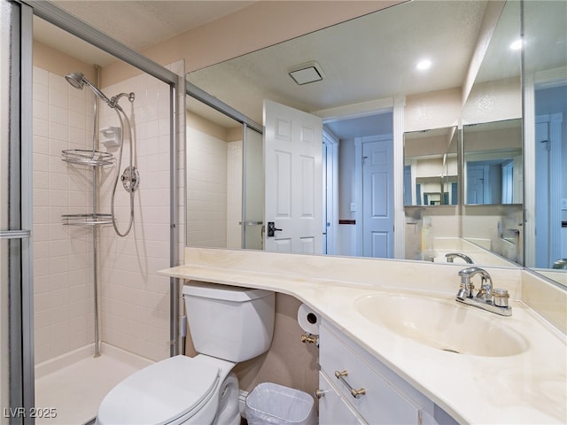 bathroom with vanity, toilet, and tiled shower