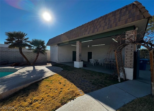 back of property featuring a fenced in pool and a patio