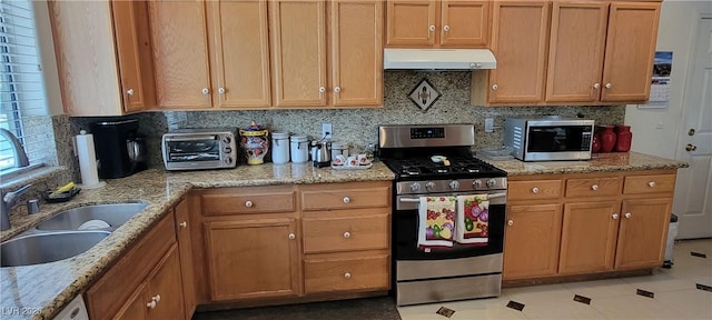 kitchen featuring sink, light tile patterned floors, light stone countertops, appliances with stainless steel finishes, and tasteful backsplash