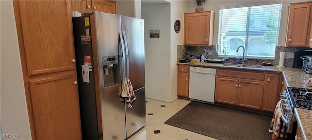 kitchen with light stone counters, sink, stainless steel appliances, and tasteful backsplash