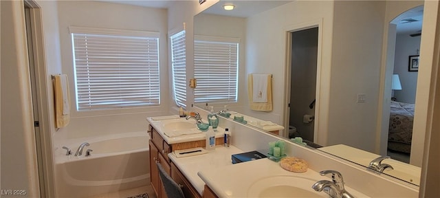 bathroom with a washtub, vanity, and toilet