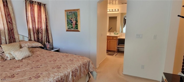 bedroom featuring connected bathroom and light colored carpet