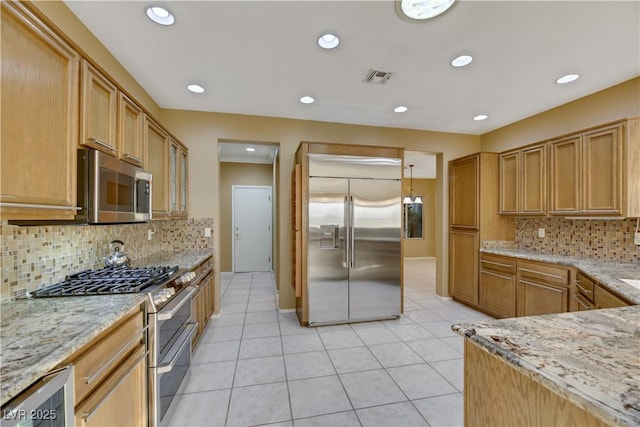 kitchen featuring tasteful backsplash, light stone counters, light tile patterned floors, and high end appliances