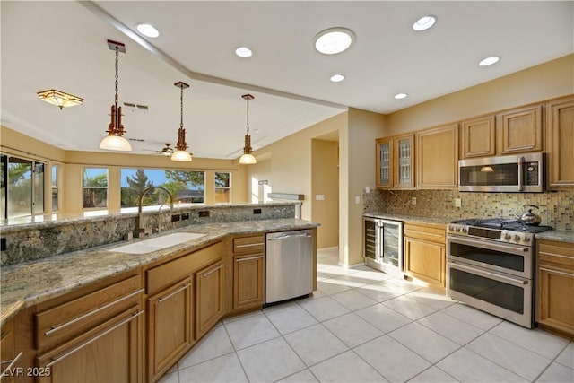 kitchen featuring appliances with stainless steel finishes, light stone counters, sink, pendant lighting, and wine cooler