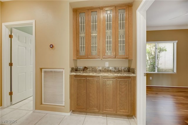 bar featuring light stone countertops, light tile patterned floors, and crown molding