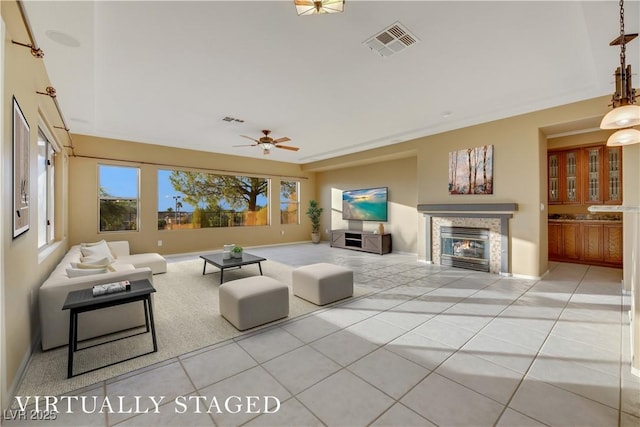 tiled living room with a stone fireplace and ceiling fan