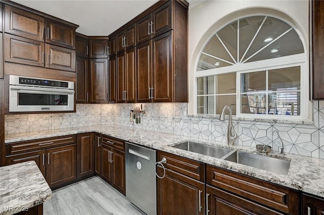 kitchen featuring light stone counters, sink, light wood-type flooring, and stainless steel appliances