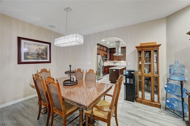 dining area with light hardwood / wood-style floors and a notable chandelier