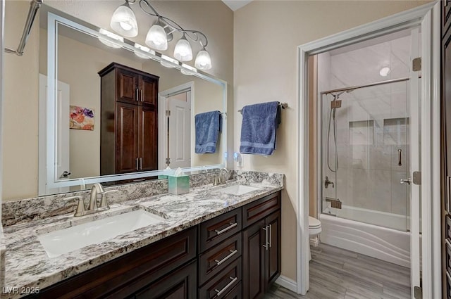 full bathroom featuring vanity, hardwood / wood-style flooring, toilet, and bath / shower combo with glass door