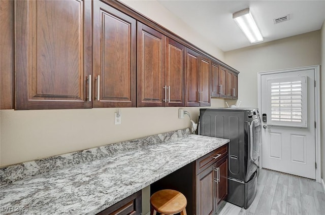 laundry area featuring washer and dryer, light hardwood / wood-style floors, and cabinets