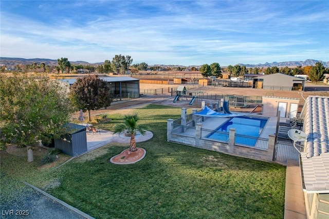 view of swimming pool featuring a mountain view, a yard, and a patio area