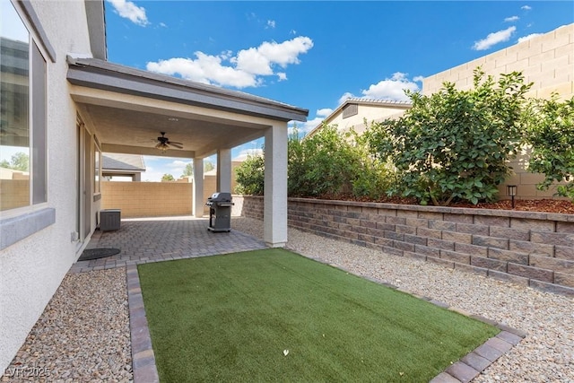 view of yard with ceiling fan, cooling unit, and a patio