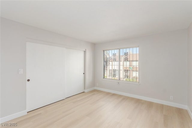 unfurnished bedroom with light wood-type flooring and a closet