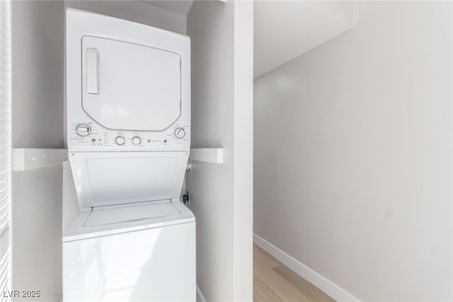 laundry area with light hardwood / wood-style floors and stacked washer and dryer