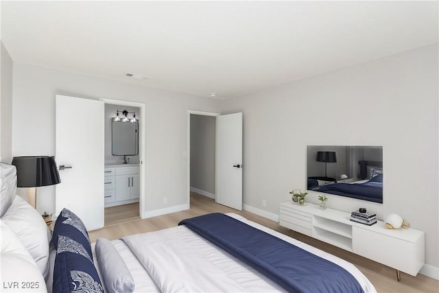 bedroom featuring ensuite bathroom and light hardwood / wood-style floors