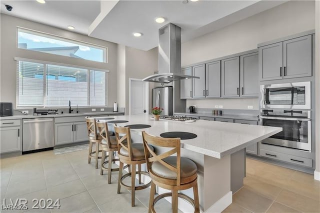10301 Fairview Ridge Ct, Las Vegas, NV 89166 - kitchen featuring a kitchen breakfast bar, gray cabinets, island exhaust hood, appliances with stainless steel finishes, and light tile patterned floors