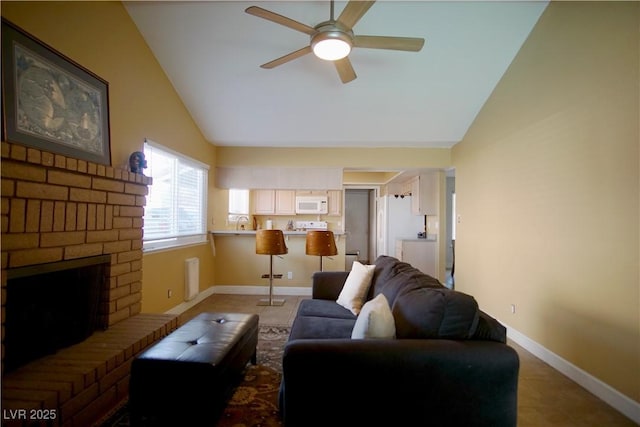 living room featuring a fireplace, vaulted ceiling, sink, and ceiling fan