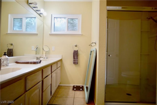 bathroom with tile patterned flooring, vanity, a shower with shower door, and toilet