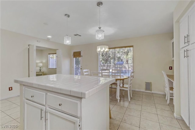 kitchen with tile countertops, pendant lighting, a notable chandelier, a kitchen island, and white cabinetry