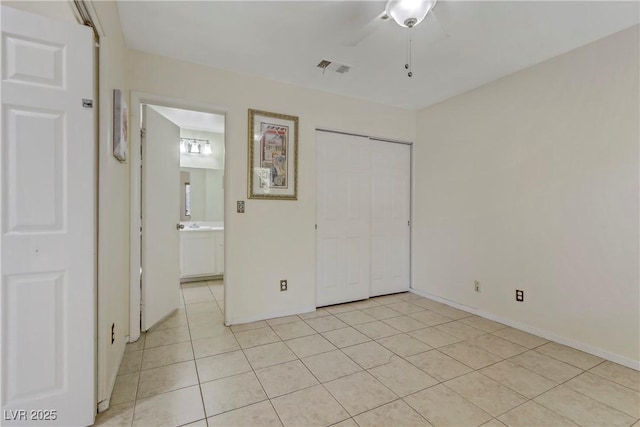 unfurnished bedroom featuring ensuite bath, ceiling fan, a closet, and light tile patterned flooring