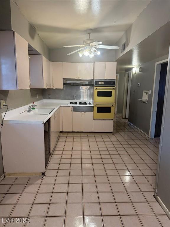 kitchen with ceiling fan, double oven, sink, light tile patterned floors, and stovetop