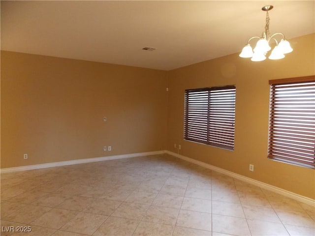 tiled spare room with a chandelier