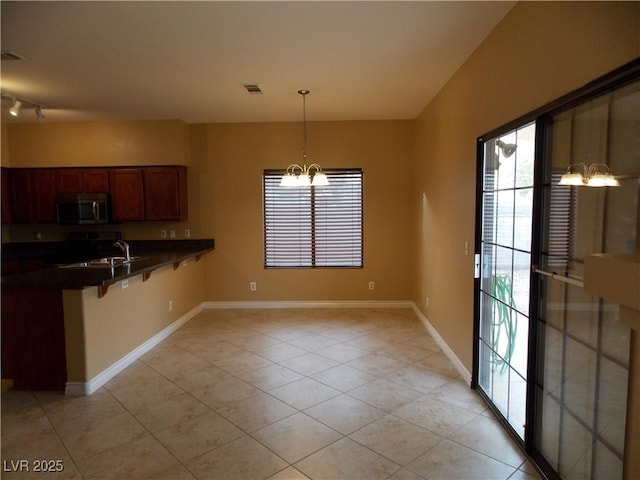 kitchen with kitchen peninsula, stove, a chandelier, decorative light fixtures, and light tile patterned flooring