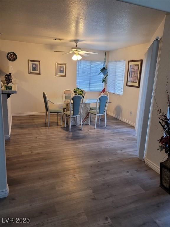 dining space with ceiling fan, dark hardwood / wood-style floors, and a textured ceiling