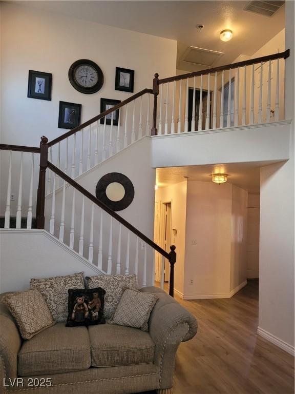 stairs with wood-type flooring and a towering ceiling