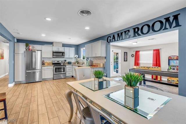 kitchen featuring a wealth of natural light, white cabinetry, and appliances with stainless steel finishes