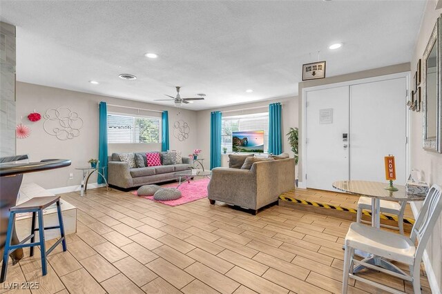 living room with ceiling fan, a healthy amount of sunlight, and a textured ceiling