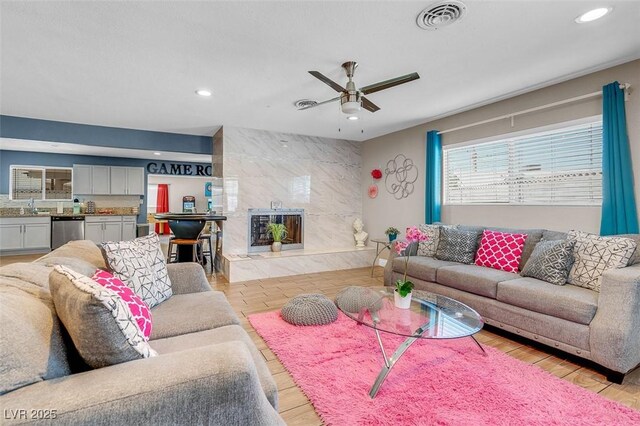 living room featuring ceiling fan, light wood-type flooring, and sink